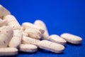 Many white medicine tablets on blue background. White pills, concept Ã¢â¬â pharmacy. Medicines drugs. Royalty Free Stock Photo